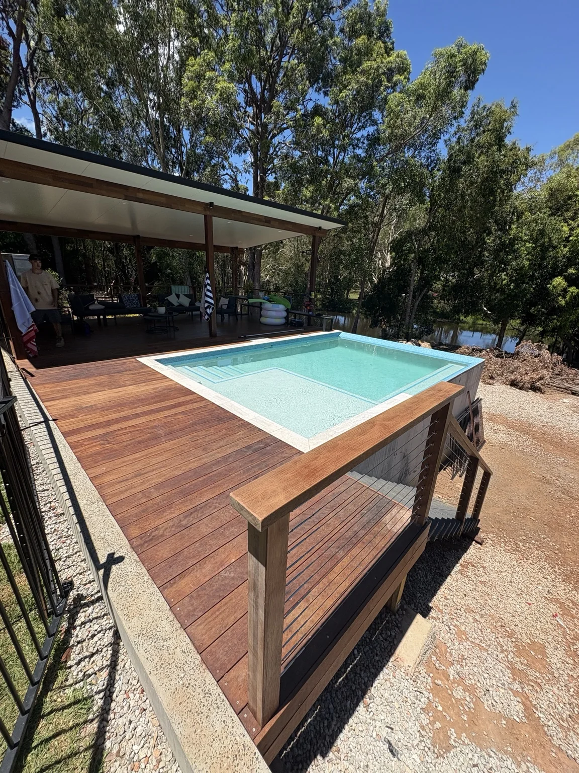 Finished timber deck surrounding a swimming pool and covered outdoor living area